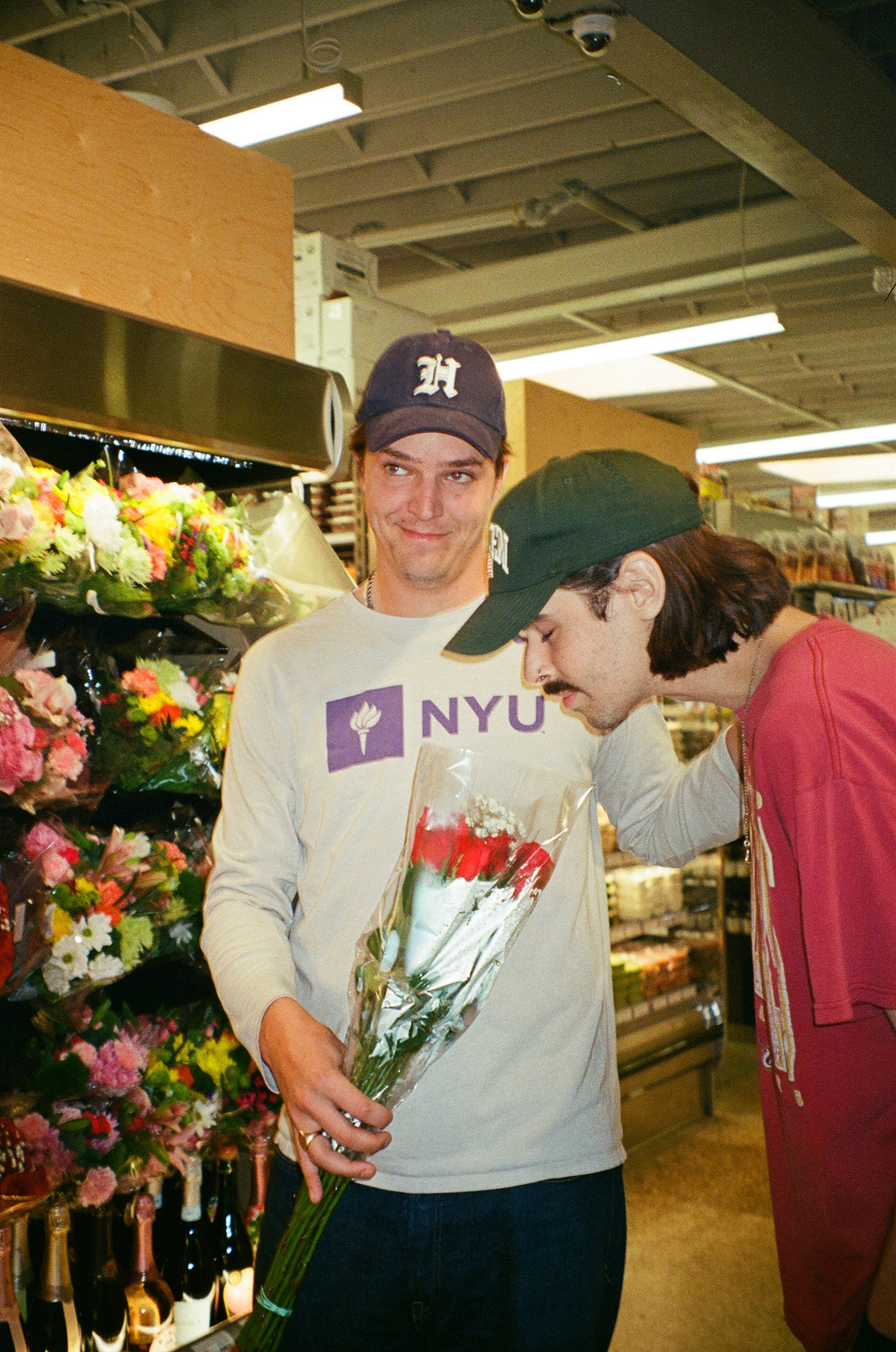 Two friends holding flowers in a grocery store
